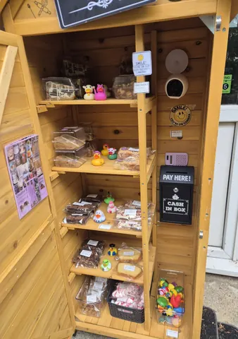 A small wooden structure with a sign that says "Pay Here" and a cash register.