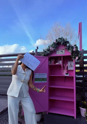 A woman is standing in front of a pink building with a sign that says "food allergy".