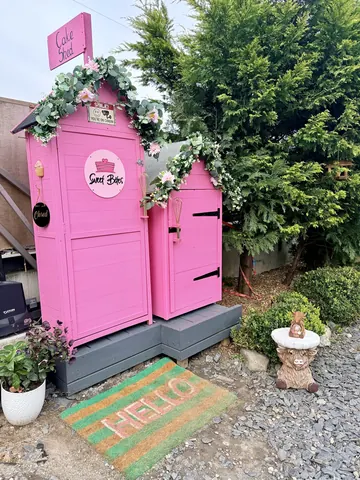 A pink shed with a sign that says "Sweet Berry" on it.