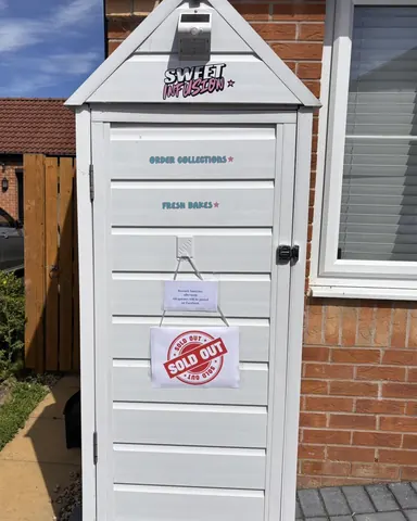 A white shed with a sign on it.