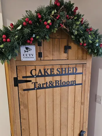 A wooden sign with a cake shop logo on it.