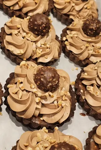 A close up of a chocolate dessert with nuts on top.