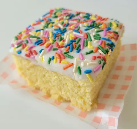 A piece of cake with sprinkles on a paper towel.