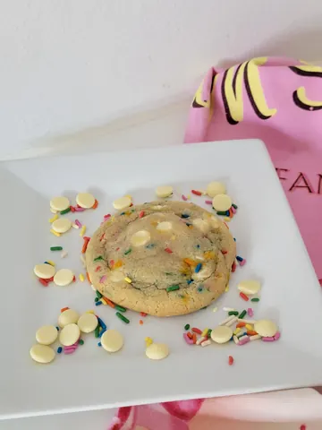 A white plate with a cookie on it.