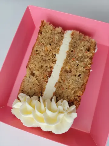A slice of cake with white frosting and a white whipped cream topping.