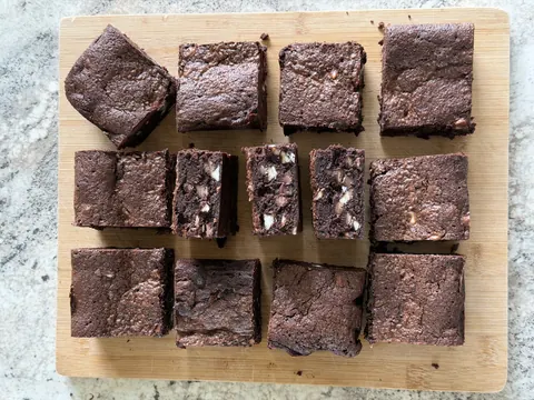 A wooden cutting board with a variety of brownies on it.