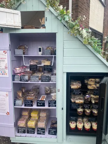 A small blue building with a refrigerator inside.