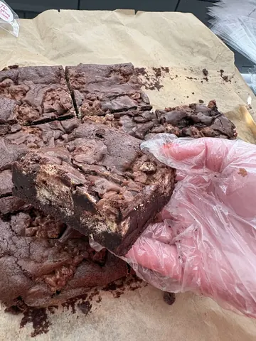 A hand is holding a piece of chocolate cake.
