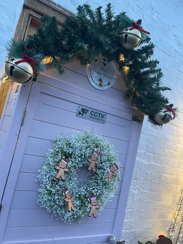 A pink door with a wreath and a sign that says "the pake shop".