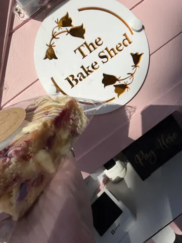 A slice of cake is being held by a person in front of a sign.