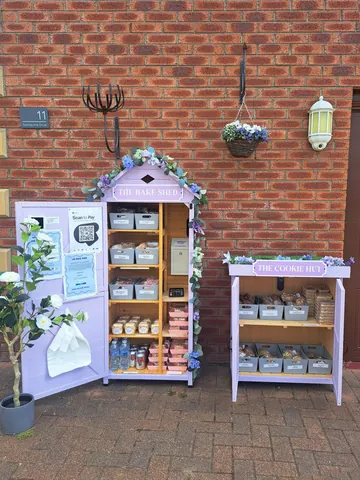 A purple food stand with a sign that says "The Cookie Hut" and a potted plant.
