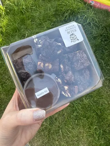 A person holding a box of chocolate desserts.