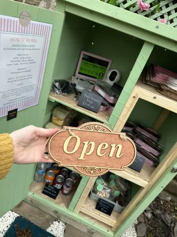 A person is holding a wooden sign that says "open."