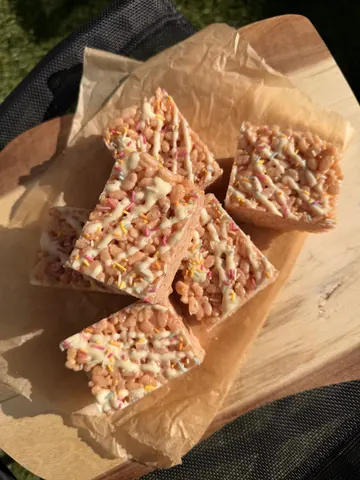 A wooden table with a tray of cake squares.