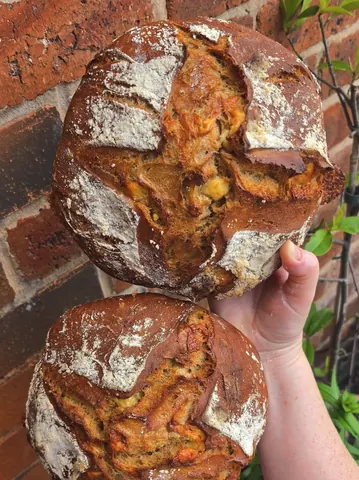 A person is holding two loaves of bread.