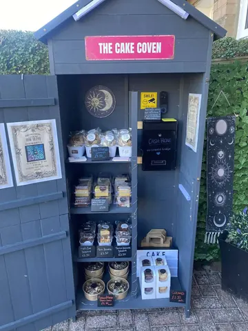A small building with a sign that says "The Cake Coven" on it.