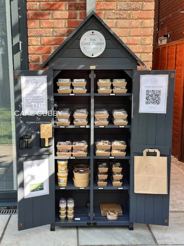 A small wooden building with a sign that says "Cake Cube" on it.