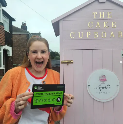 A woman is holding a sign that says "Food Hygiene Rating 5".