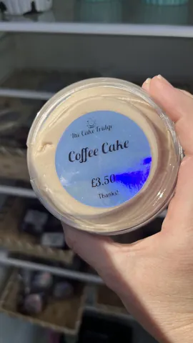 A hand holding a jar of coffee cake.