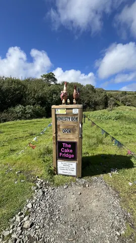 A sign for a cake fridge is on a wooden post.