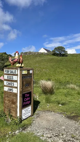 A sign for the cake fridge is in the grass.