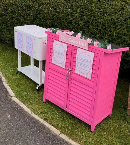 A pink and white cake stand with a pink door and a white stand.