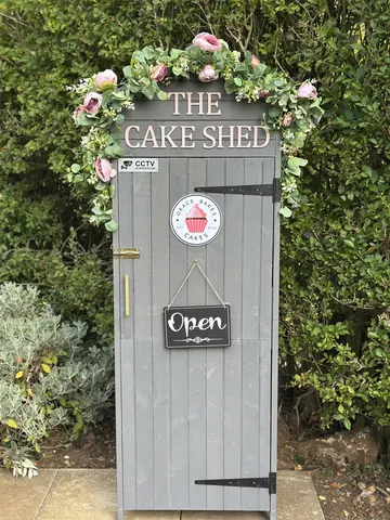 A sign that says "The Cake Shed" is in front of a building.