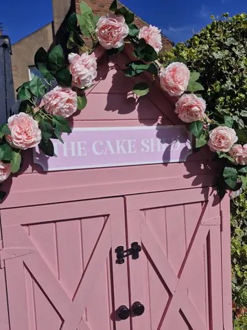 A pink door with a sign that says "The Cake Shop" on it.
