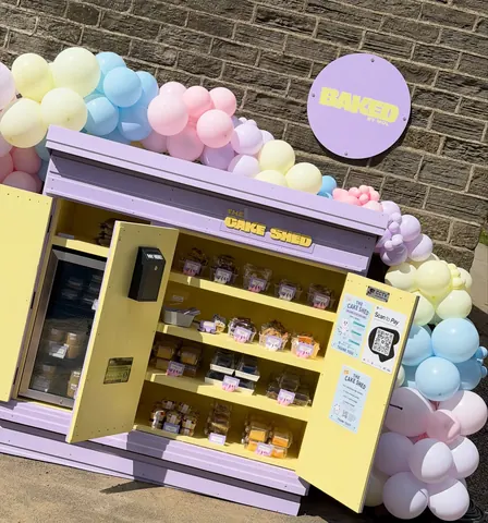 A yellow refrigerator with a purple door and a sign that says "Baked" on it.