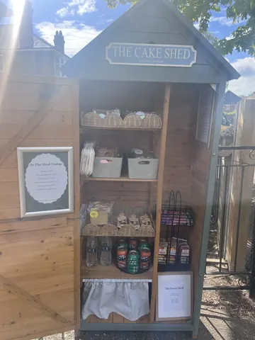 A small wooden shed with a sign that says "The Cake Shed" on it.