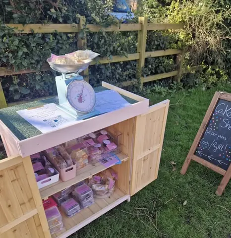 A wooden box with a scale and a sign that says "cake shop" is outside.
