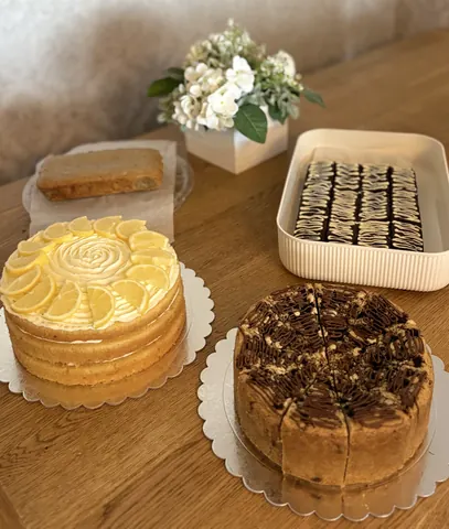 A table with a cake and a flower arrangement on it.