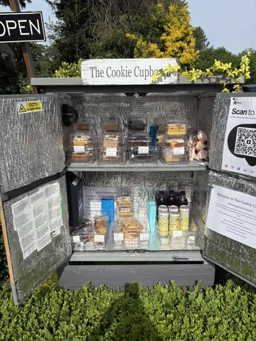 A display case with a sign that says "The Cookie Cupcake" and a sign that says "Scan to order".