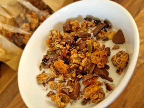 A bowl of cereal with chocolate chips and nuts.
