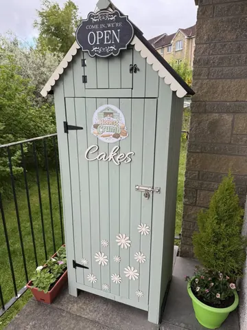 A small green shed with a sign that says "Open" on it.