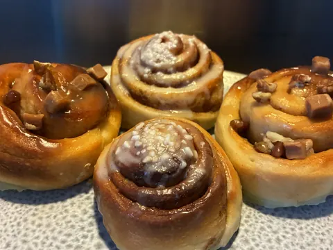 Four pastries with white icing and brown toppings.