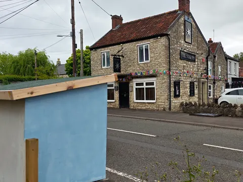 A blue building with a black door and a white sign.