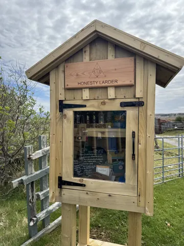 A wooden structure with a sign that says Honesty Larder.