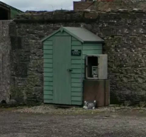 A green shed with a sign on it.