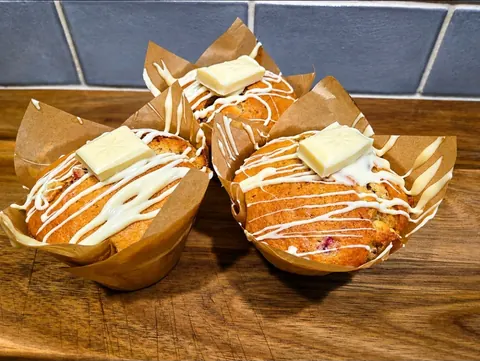A wooden table with two muffins on it.