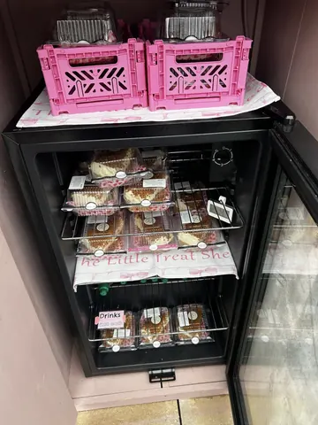 A black refrigerator with pink boxes on top.
