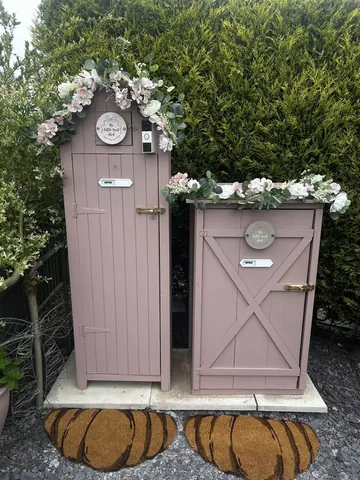 Two pink toilets with flowers on top of them.