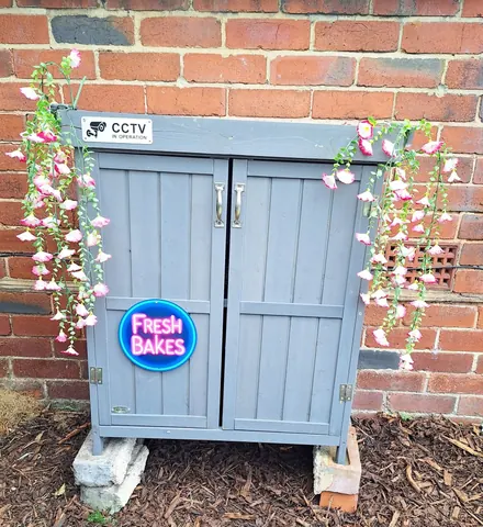 A small grey building with a sign that says "Fresh Bakes" on it.