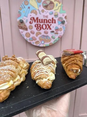 A sign that says "The Munch Box" is on a pink wall.