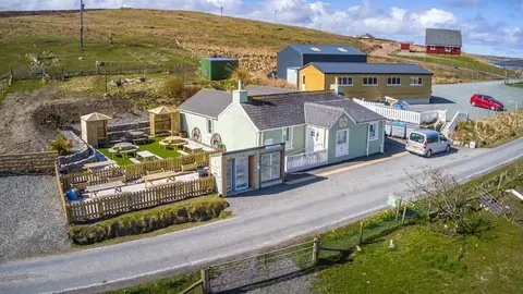 A white house with a blue roof and a green roof.