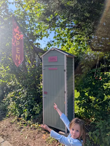 A small green shed with a pink door.