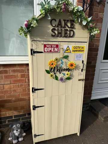 A small white shed with a sign that says "welcome" on it.