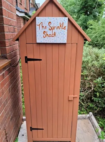 A small wooden shed with a sign on it.