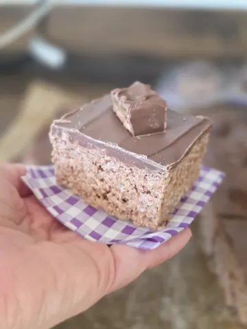 A hand holding a piece of cake.