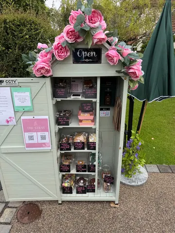 A small green building with a pink sign that says "open" on it.